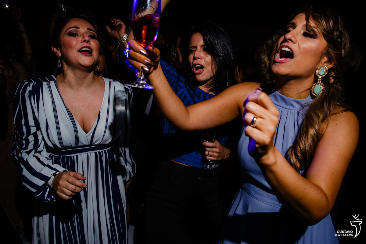 amigas dançam e cantam com as taças para cim