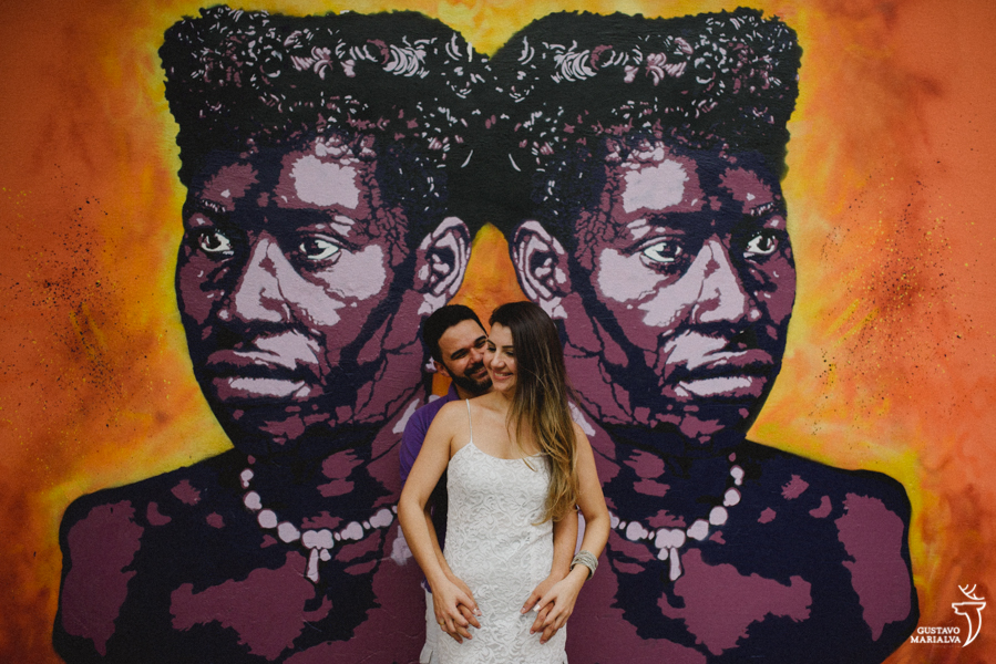 noivos posando em frente a um grafite