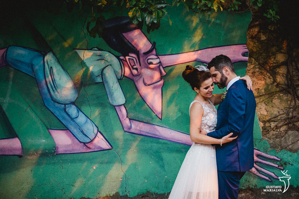 noivos posando em frente a parede com grafite