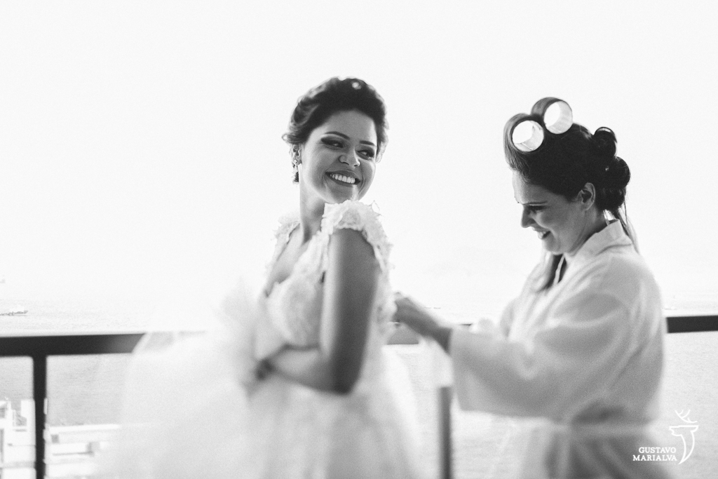 mãe da noiva fechando o vestido de casamento durante o making of do casamento