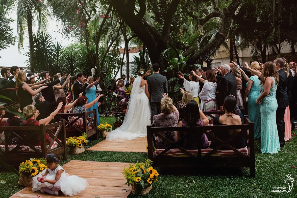 noivos sendo abençoados pelos convidados durante a cerimônia de casamento