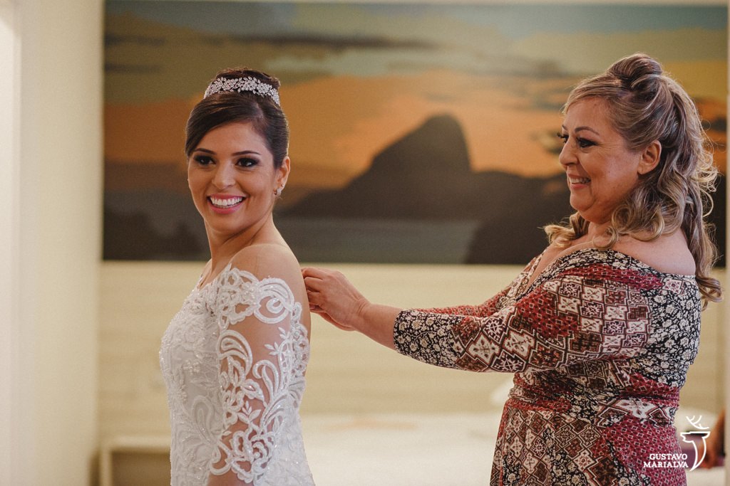 mãe fechando o vestido da noiva durante o making of de casamento