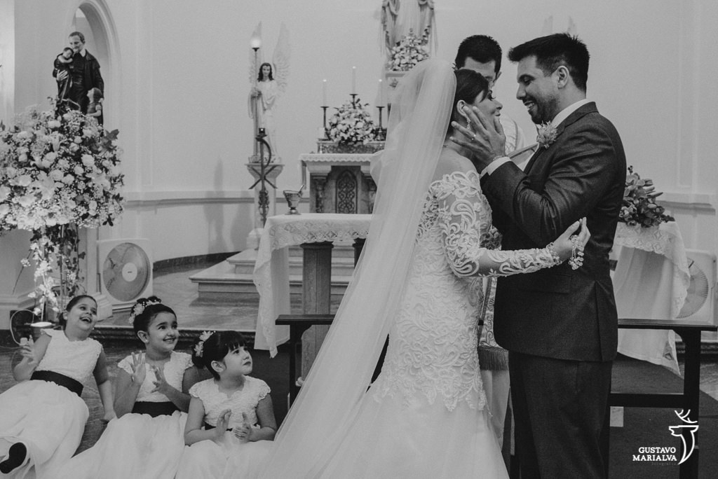 noivos se beijando e daminhas emocionadas na cerimônia de casamento