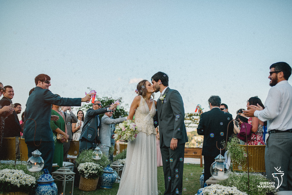 noivos se beijando na saída da cerimônia de casamento com bolinhas de sabão