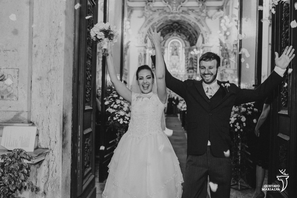 noivos comemorando o casamento na saída da cerimônia