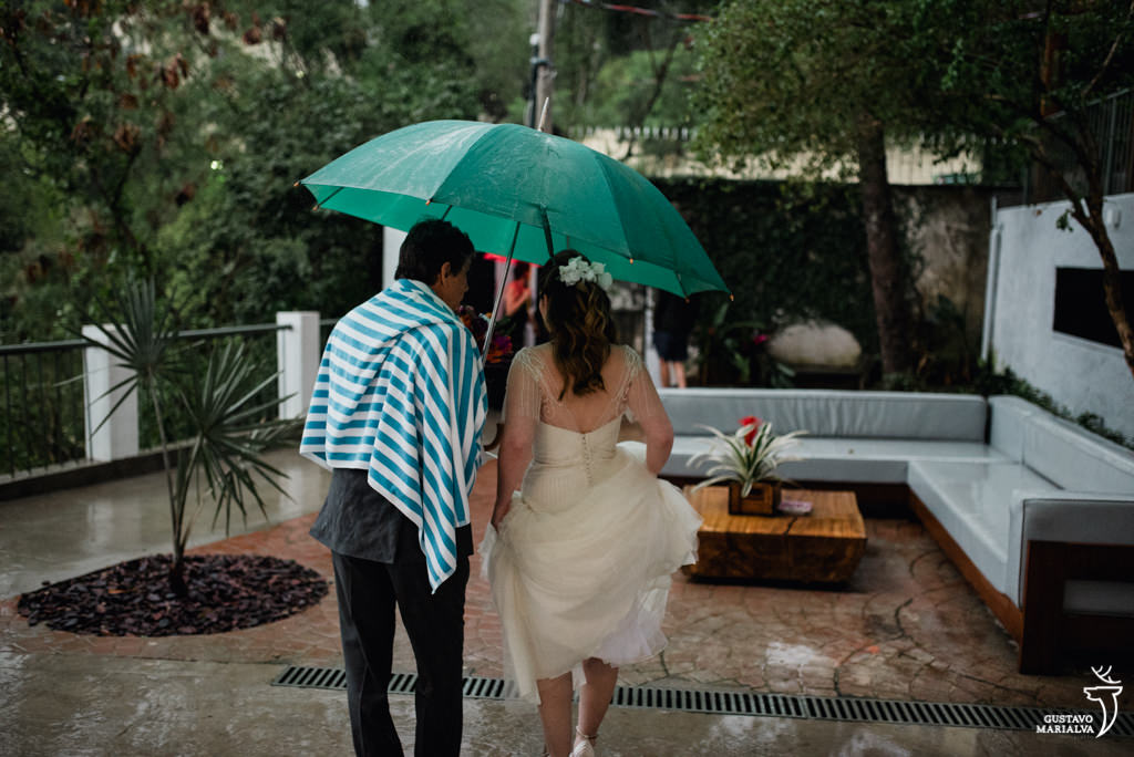 noiva indo para o casamento na chuva embaixo do guarda-chuva