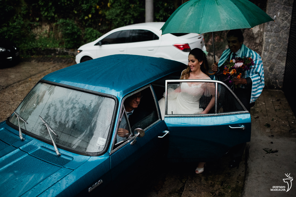 noiva indo para o casamento na chuva embaixo do guarda-chuva