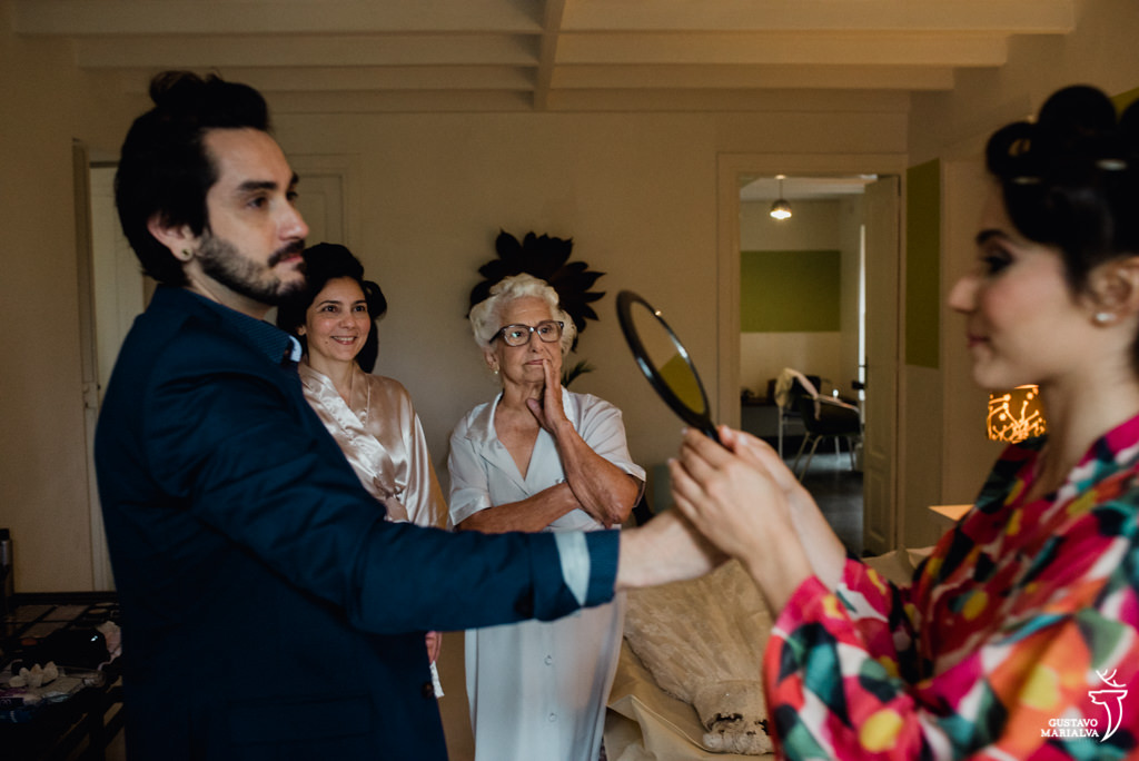 noiva se olhando no espelho e mãe e avó emocionadas