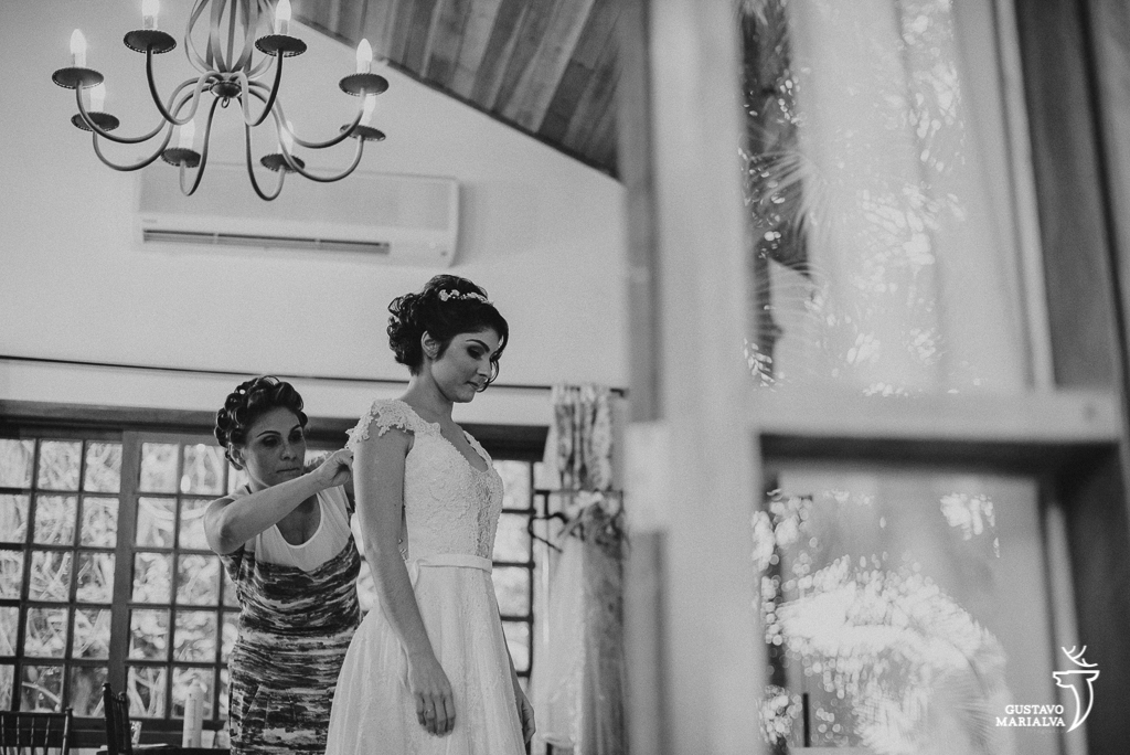 mãe da noiva fechando o vestido da noiva