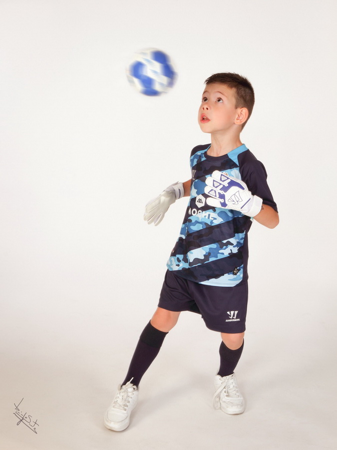 fotografia de estúdio miúdo a jogar futebol