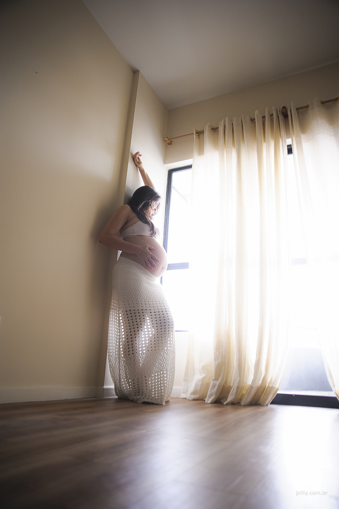 mulher gravida observa pela janela o dia chegar