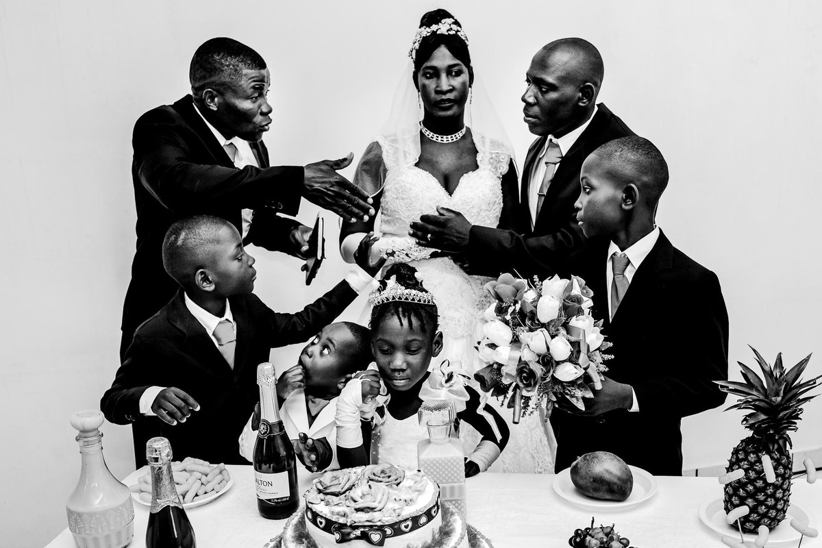 toasting the Haitian wedd next to the table is the bride with serene and deep semblance while the groom discusses with the godfather, the children look to each other and for the cake in front of them