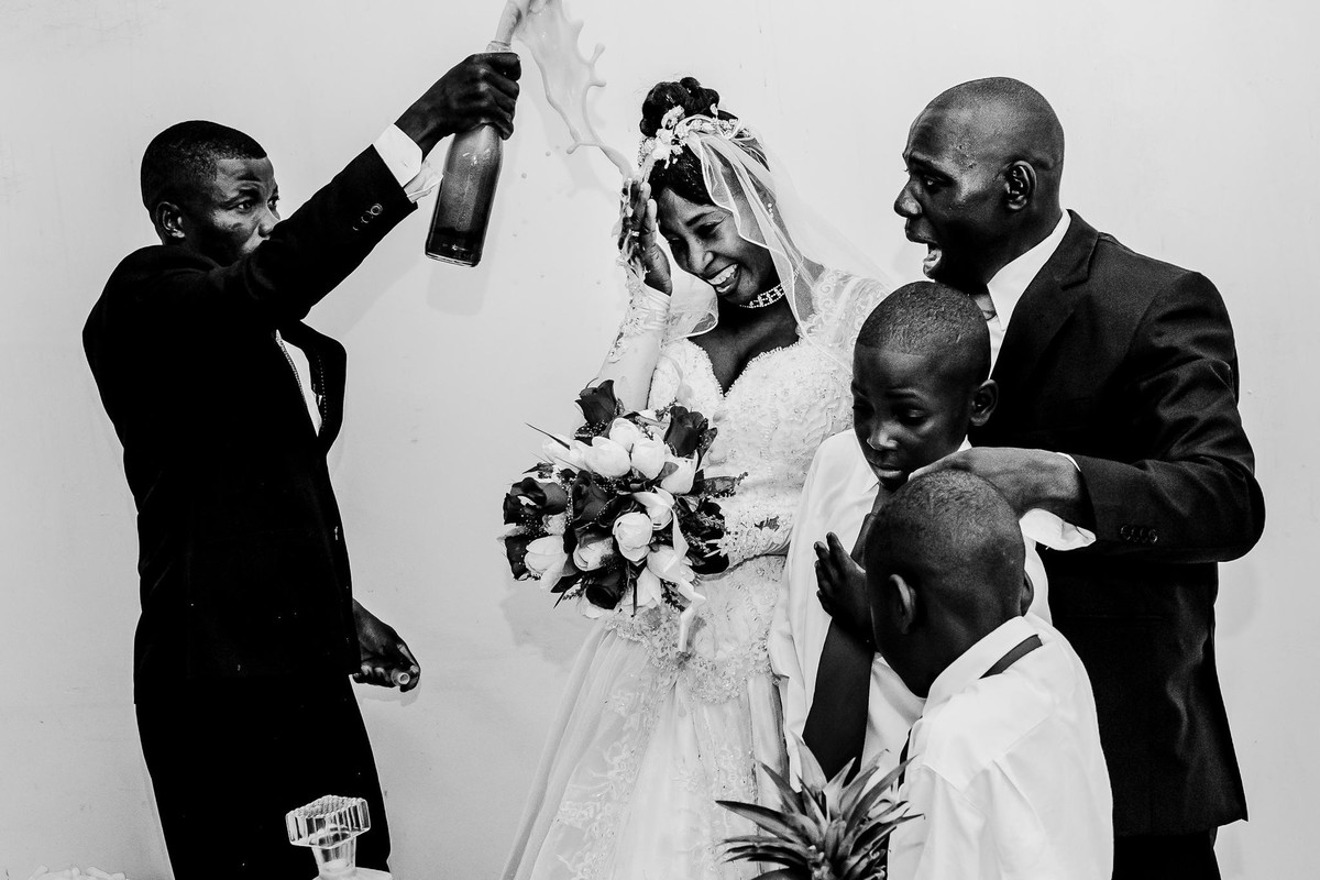 A special moment of the Haitian wedding in which the bride finally smiled while the godfather exploded the champagne in front of her next to the groom who looks at him terrified with the children