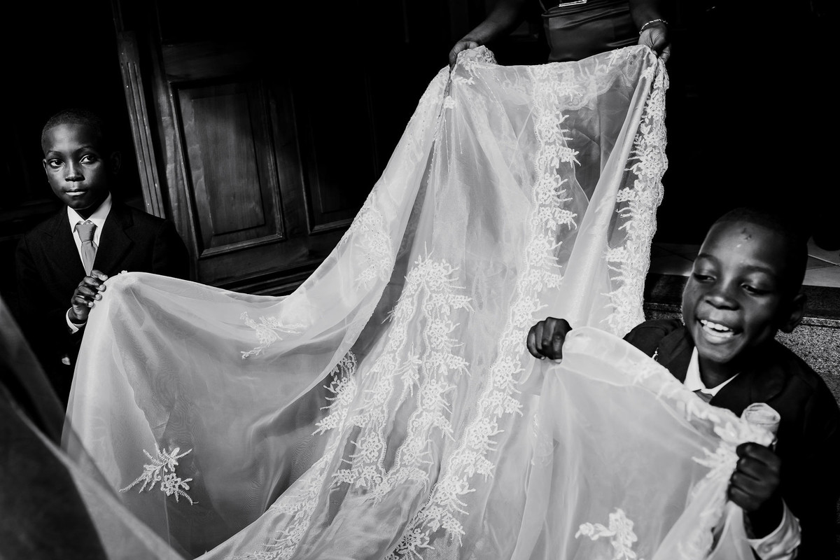 Two Haitian boys are holding the bride's veil while they are going outside the church