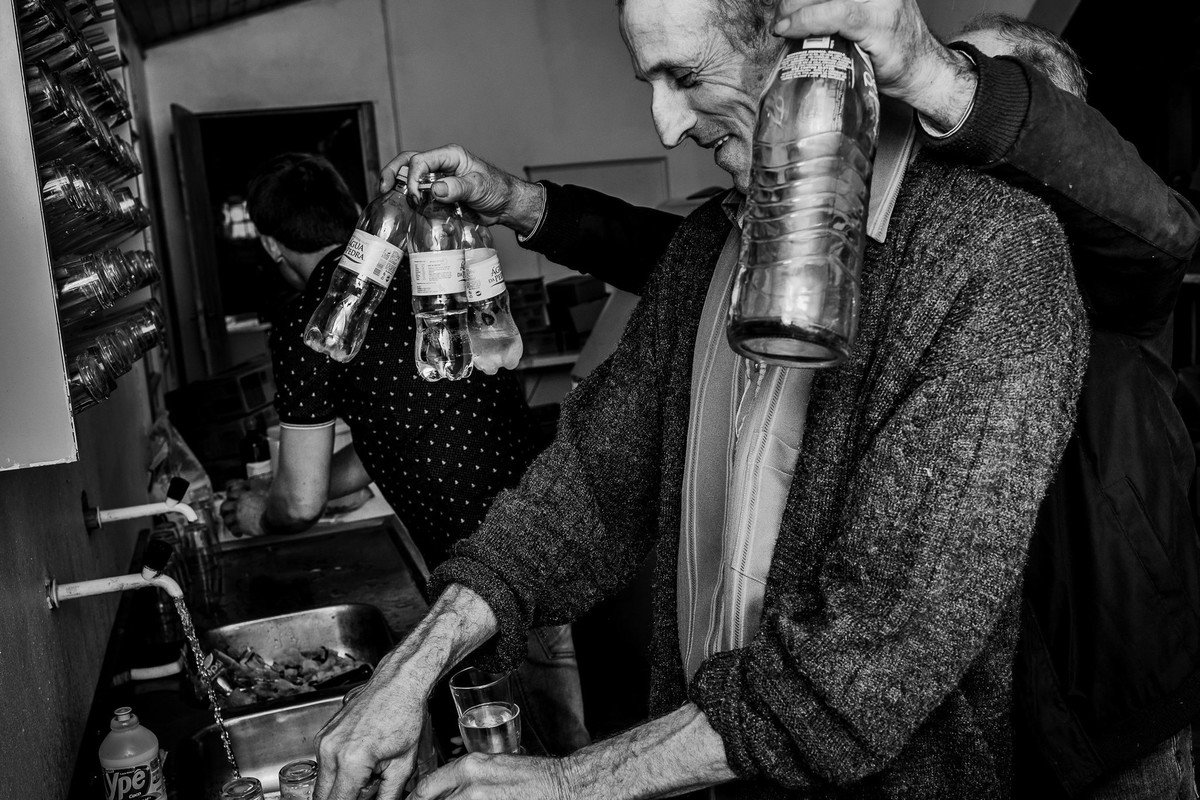 fotografia documental em preto e branco registra cena engraçada de homens na cozinha lavando a louça