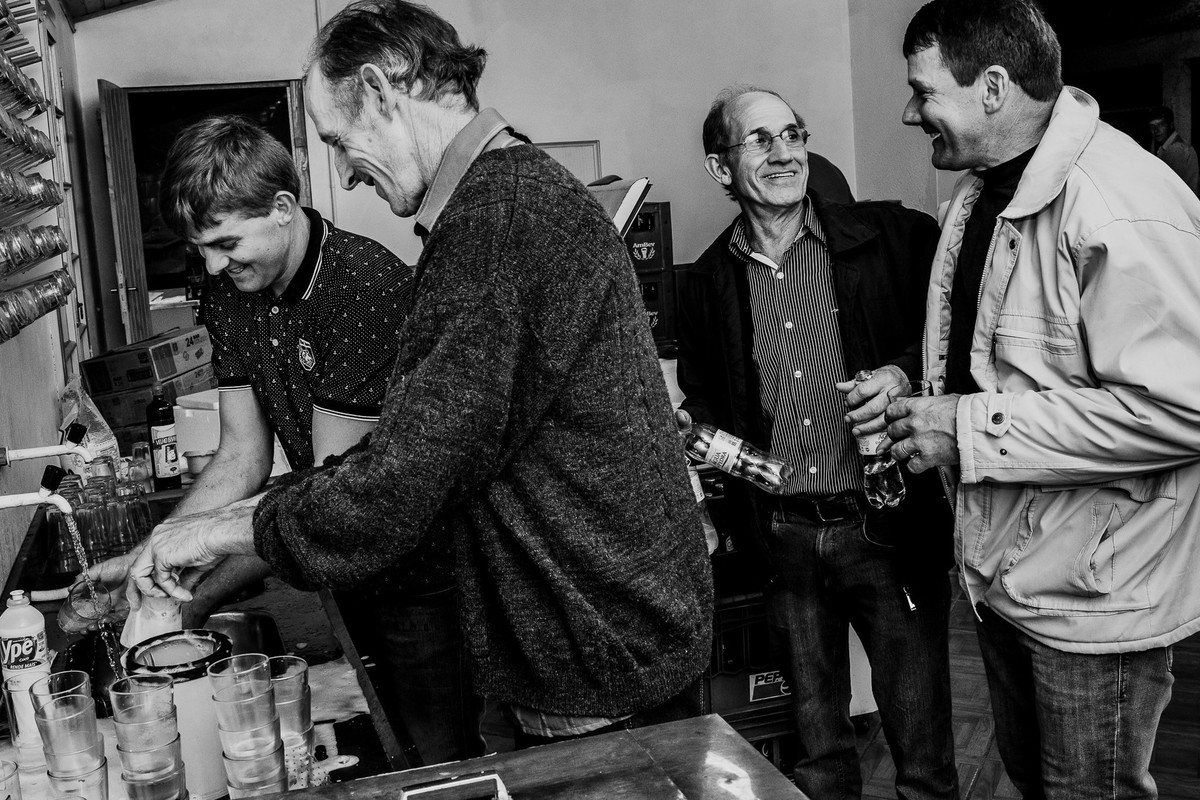 foto em preto e branco de homens se divertindo na cozinha lavando a louça