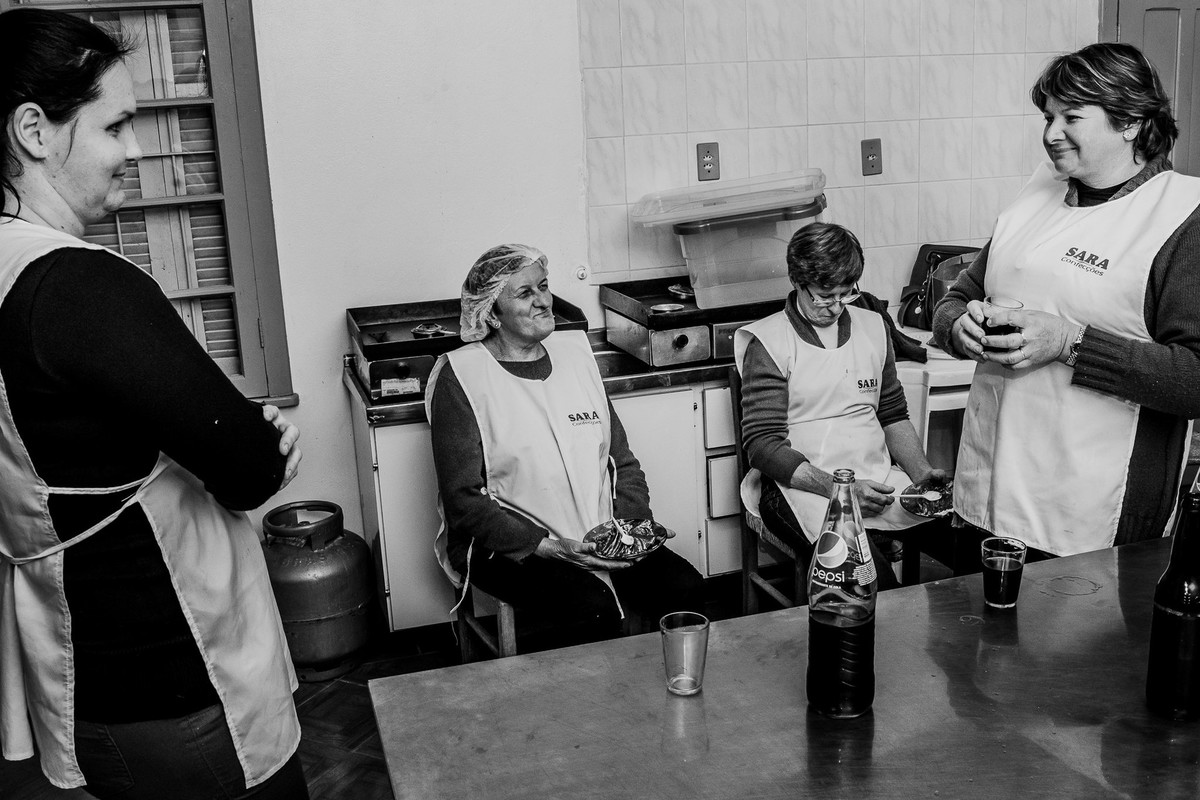 Mulheres no intervalo fotografadas na cozinha do salão de festas no interior do RS
