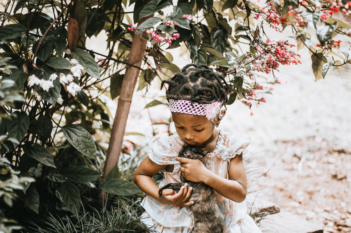Ensaio fotográfico fofo de criança haitiana brincando com filhote de gato