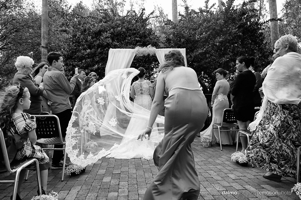 madrinha de casamento segura o véu da noiva, durante a cerimonia de casamento