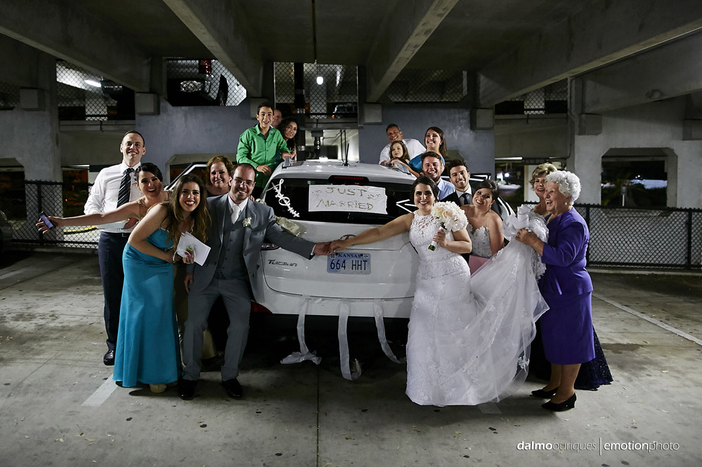 final de casamento com os noivos e convidados na frente do carro dos noivos