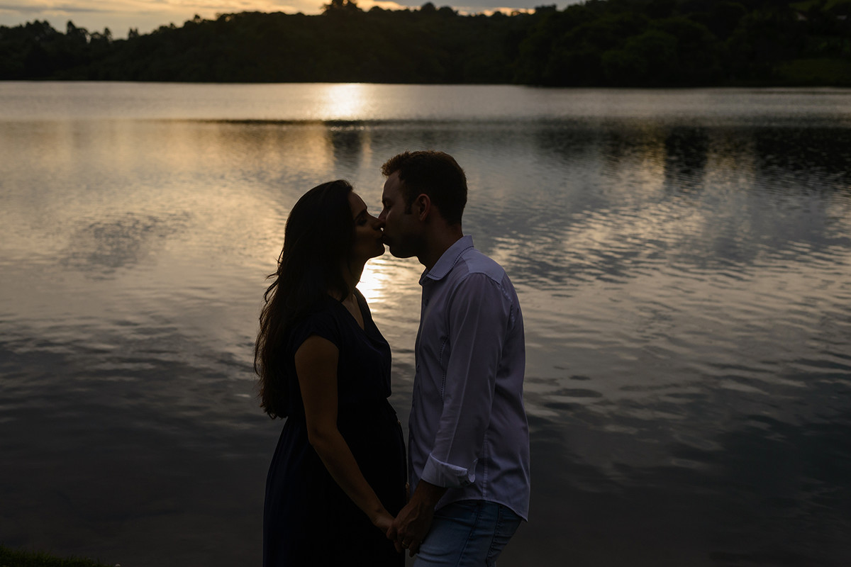 gravida gestante curitiba rio passauna passaúna com vestido de renda bege branco cabelo solto e comprido com marido esposo e natureza no fundo pôr do sol no lago