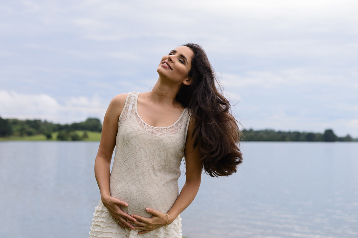 gravida gestante curitiba rio passauna passaúna com vestido de renda bege branco cabelo solto e comprido e natureza no fundo mexendo o cabelo