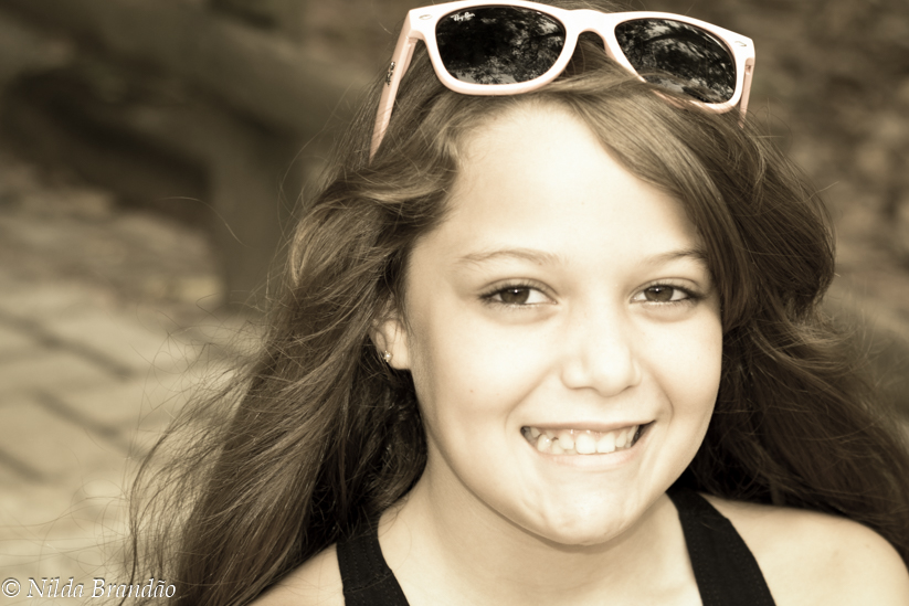 Menina de cabelo colto sorrindo usando óculos de sol