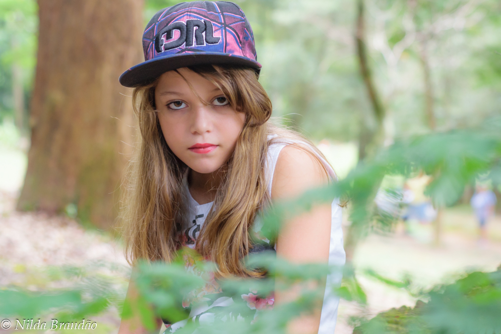 Retrato de menina com folhas desfocadas em primeiro plano