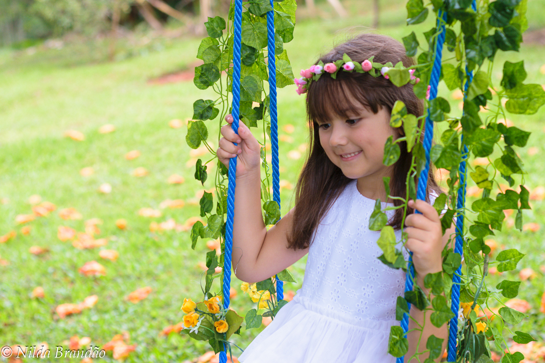 Menina no balanço enfeitado de flores
