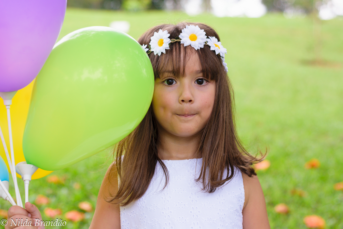 Menina com tiara de flores segurando balões
