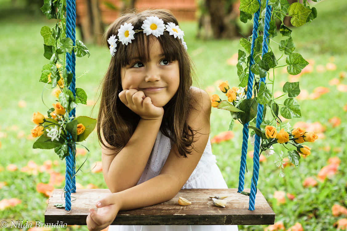 Menina com tiara de flores em balanço