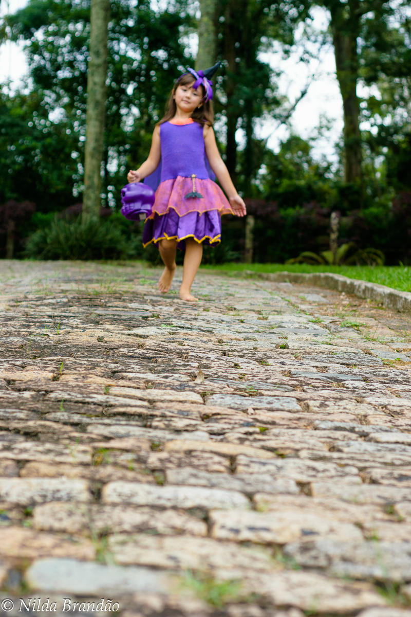 Lá vem a bruxinha! menina caminhando em estrada de pedra