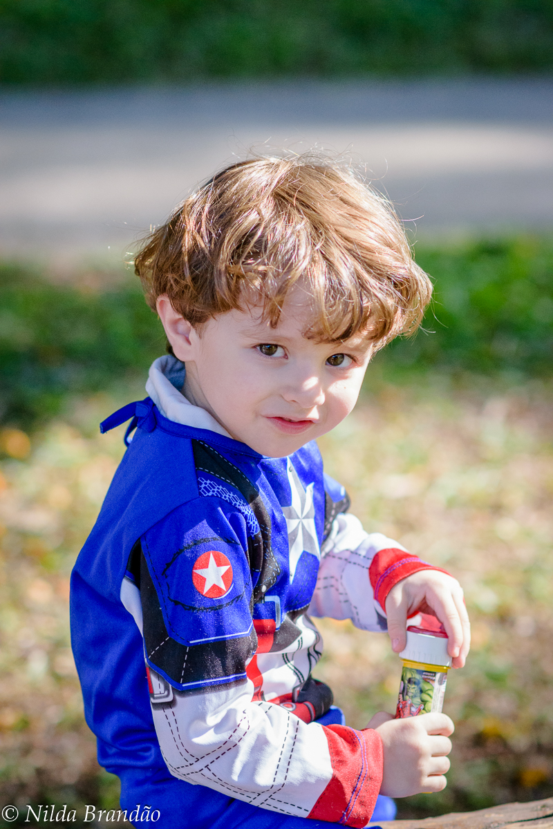 Menino fantasiado de capitão america brincando no parque