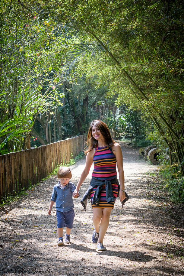 Mãe passeia com o filho em estradinha de terra com folhagem de bambu
