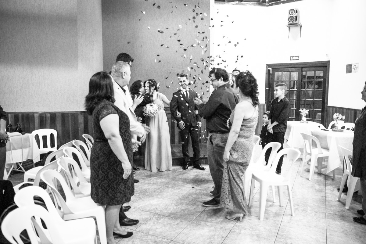 Convidados jogam confete nos noivos.