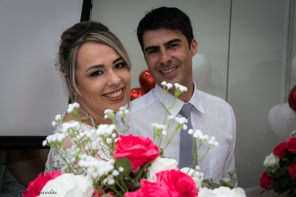 Noivos posam para fotografias junto ao arranjo de flores.