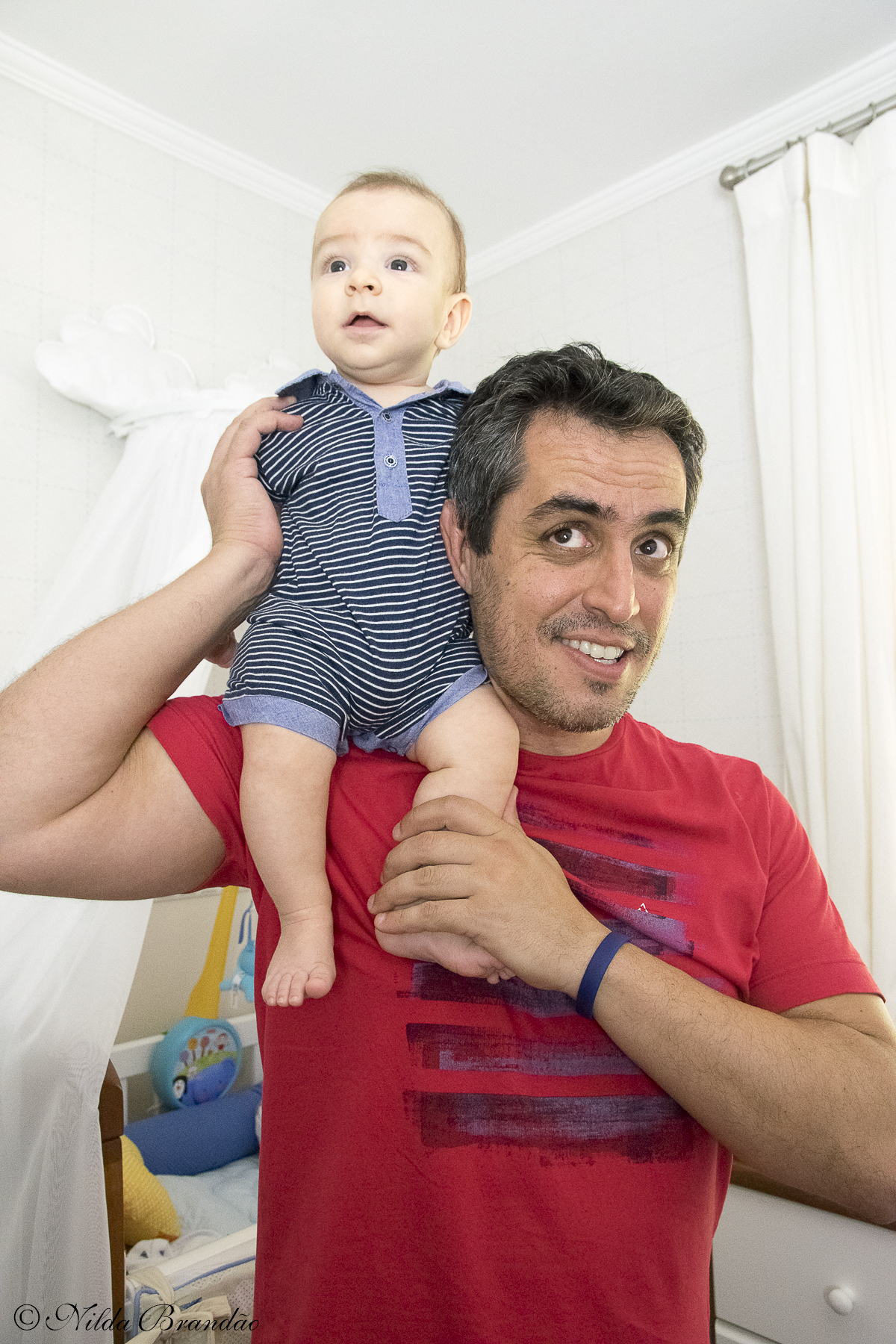 Bebê se equilibra no ombro do papai.