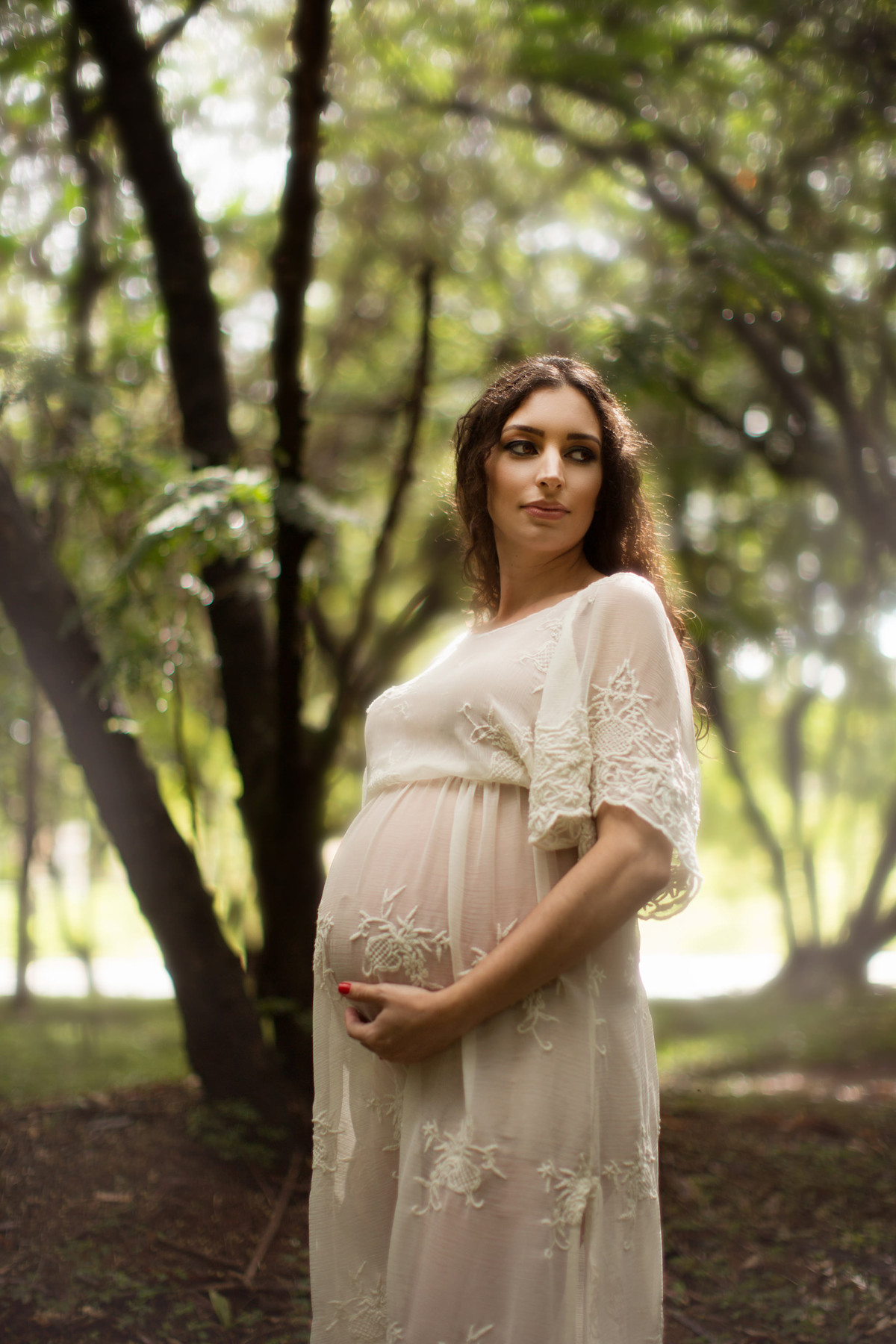 Grávida posando na floresta verde. Fotografada pelo fotógrafo de gestante Rafael Ohana em Brasília-DF.