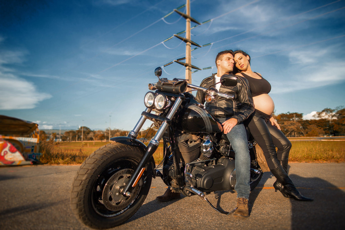 Gestante sentada com seu marido em moto Harley Davidson. Foto feita pelo fotografo de gestantes Rafael Ohana em Brasília-DF