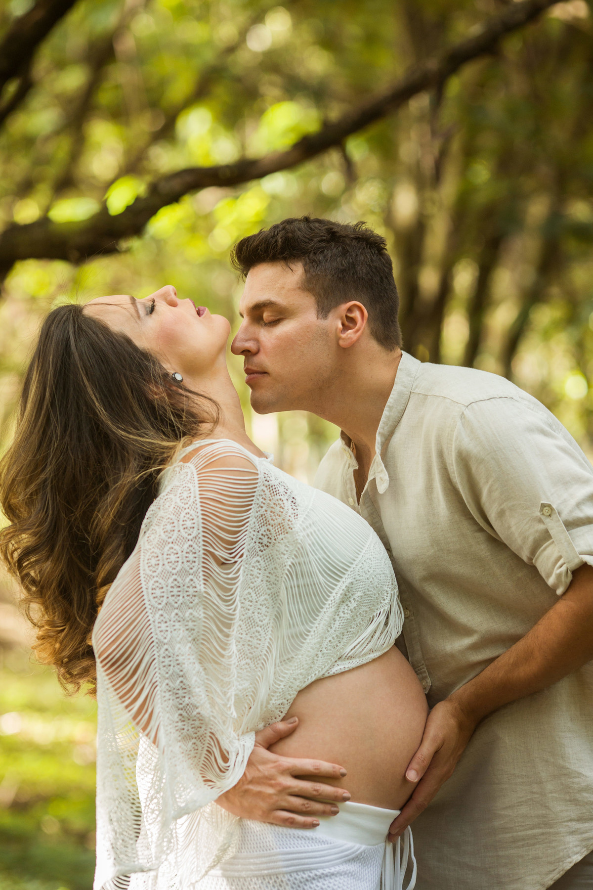 Marido beijando esposa grávida na floresta. Foto feita pelo fotografo de gestante Rafael Ohana em Brasilia-DF