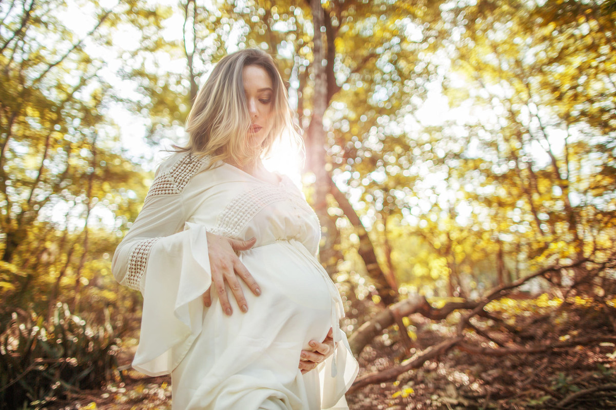 Grávida passeando sozinha na floresta alisando sua própria barriga.Foto feita pelo fotografo de gestante Rafael Ohana em Brasilia-DF