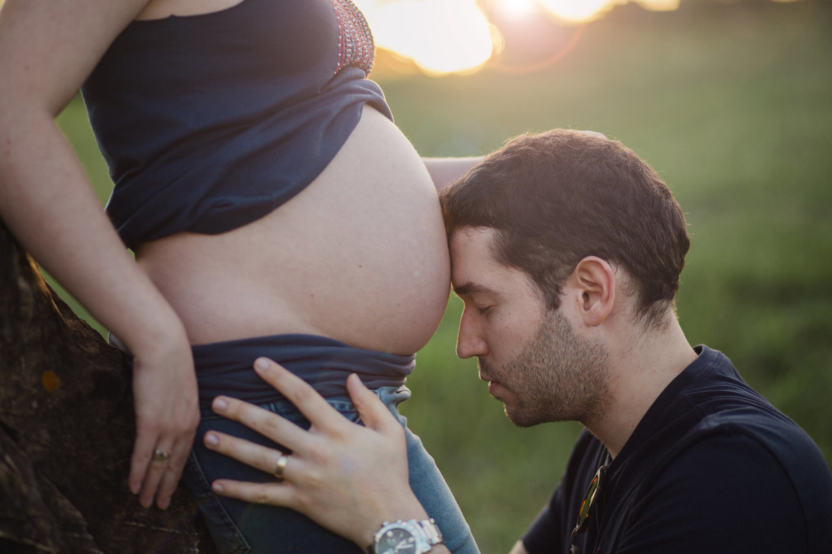 pai encostado com a cabeça na barriga da esposa grávida