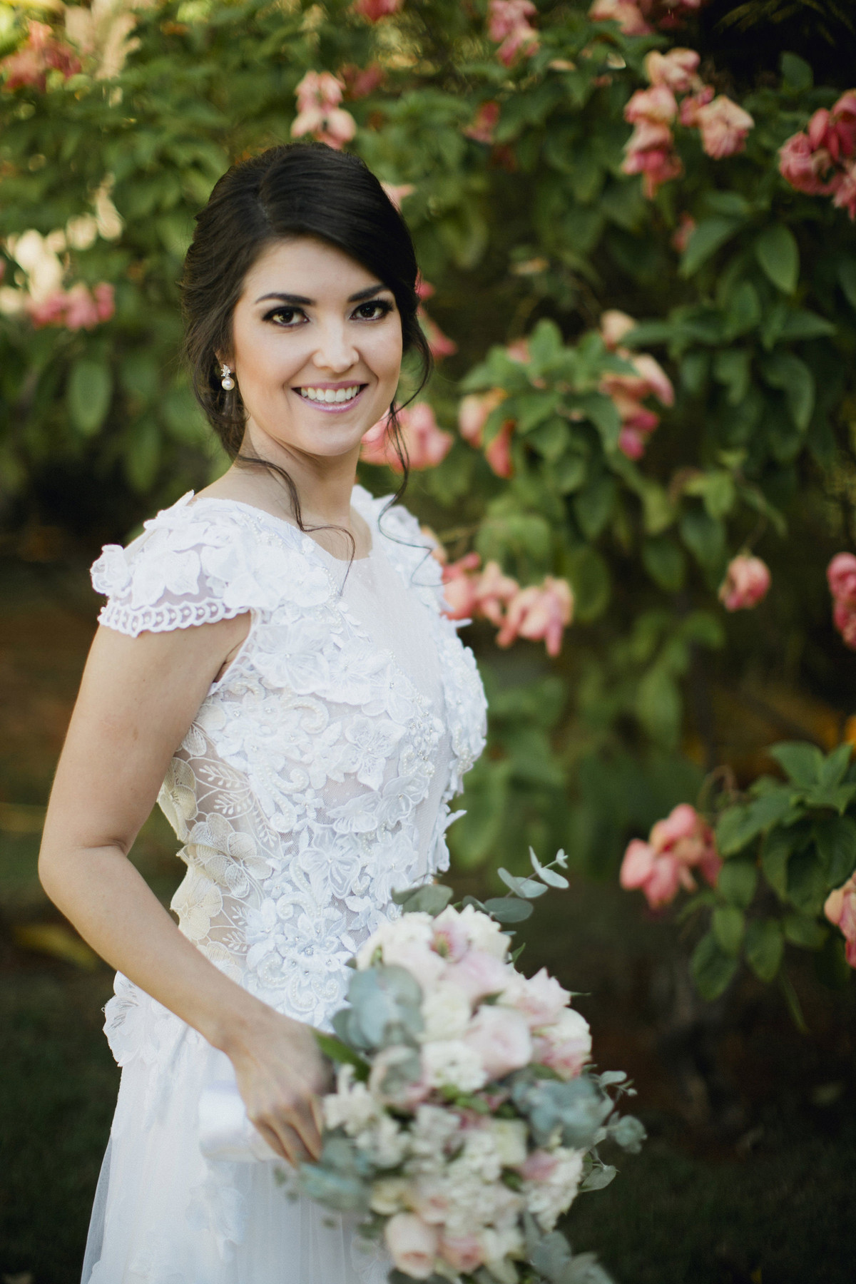 Noiva posando perto de flores rosas