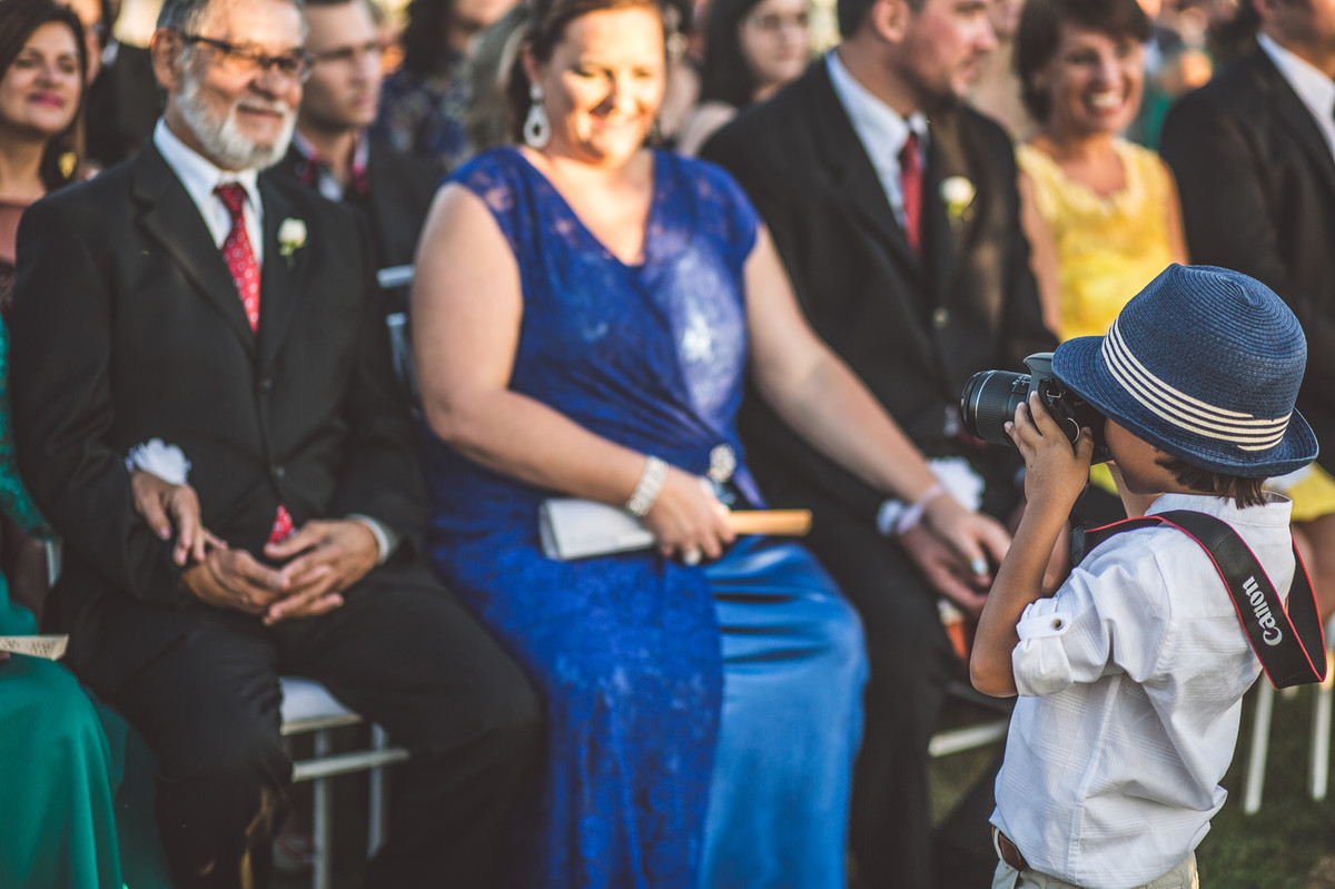 Ceriônia de casamento de Ana e Celo em Brasília-DF registrado pela equipe de Rafael Ohana Photography menino tirando fotos dos convidados