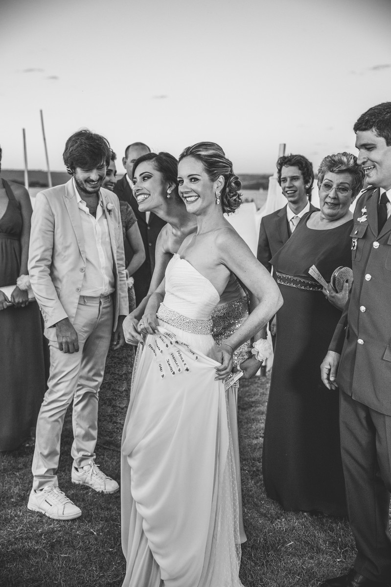 Noiva mostrando os nomes das solteiras na barra do vestido