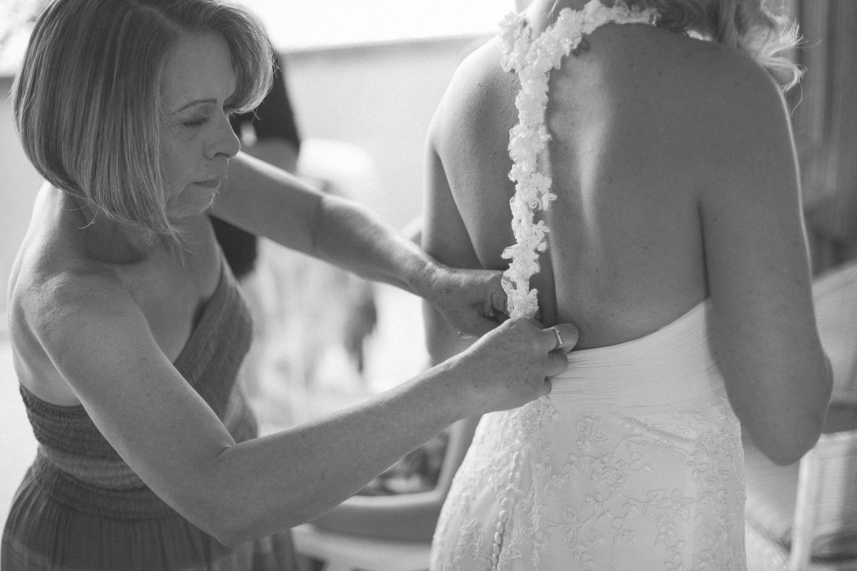 Mãe da noiva ajudando a botar o vestido de noiva