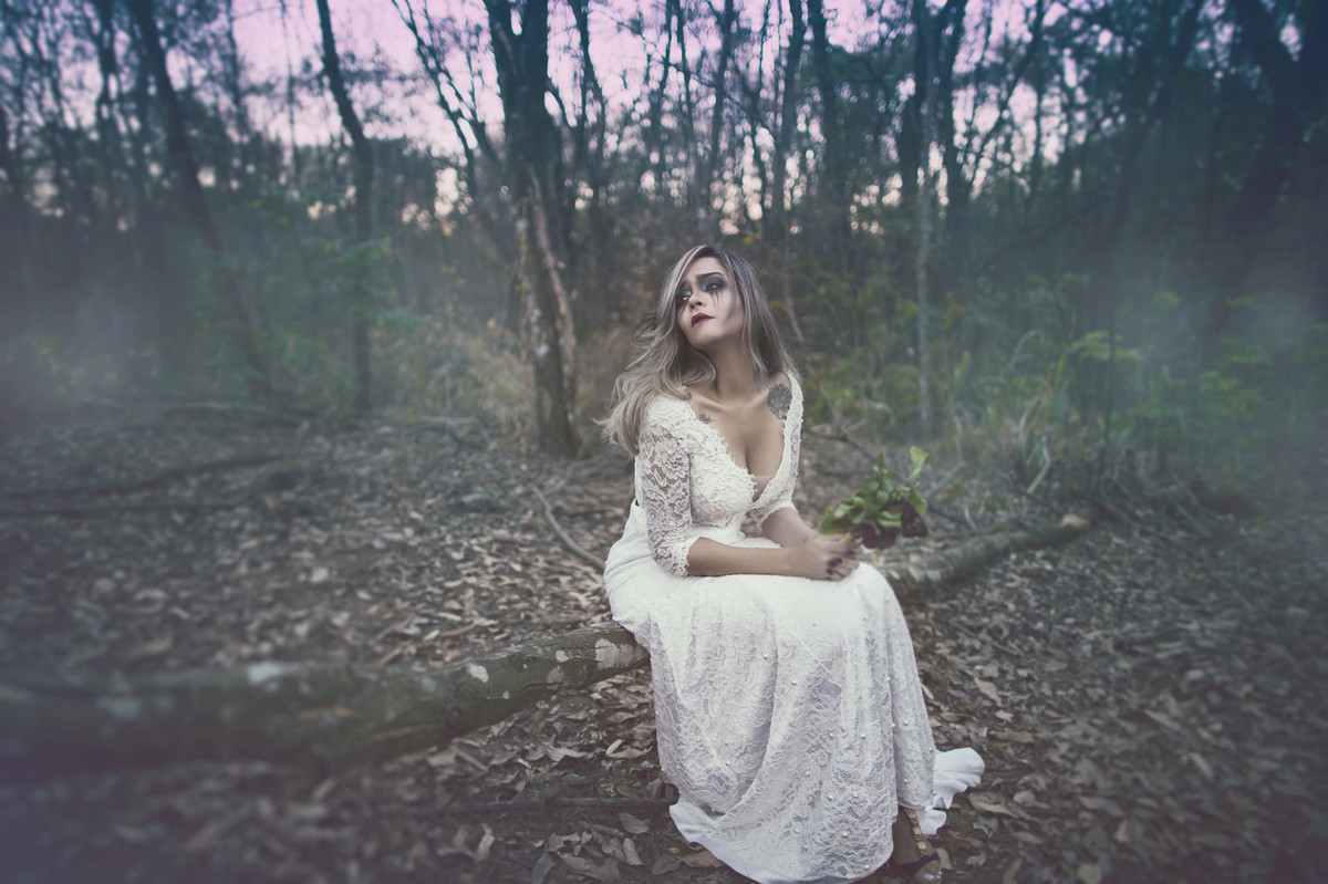 Noiva abandonada sofrendo de amor segurando flores mortas em ensaio trash the dress feito pelo fotografo de casamento Rafael Ohana em Brasilia-DF