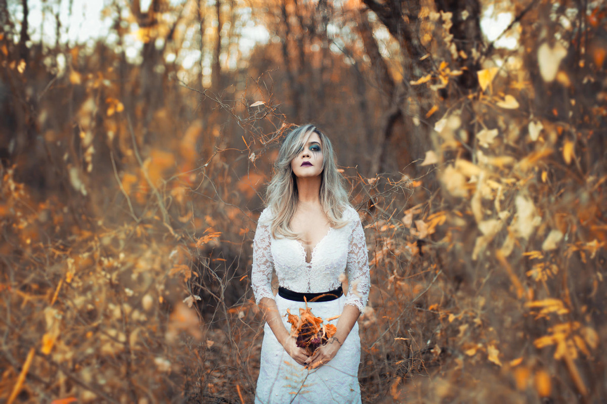 Noiva loira sozinha segurando flores mortas em ensaio Trash the Dress feito pelo fotógrafo de casamento Rafael Ohana em Brasilia-DF
