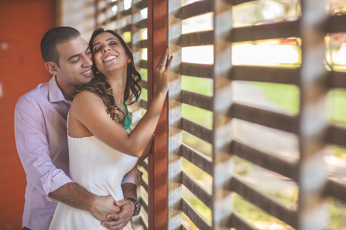 Casal se amando perto de janela de madeira. Foto feita pelo fotógrafo de casamento Rafael Ohana em Brasília-DF