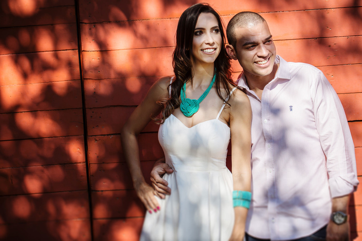 Casal sorrindo em frente e uma casa pintada de vermelho. Foto feita pelo fotógrafo de casamento Rafael Ohana em Brasília-DF